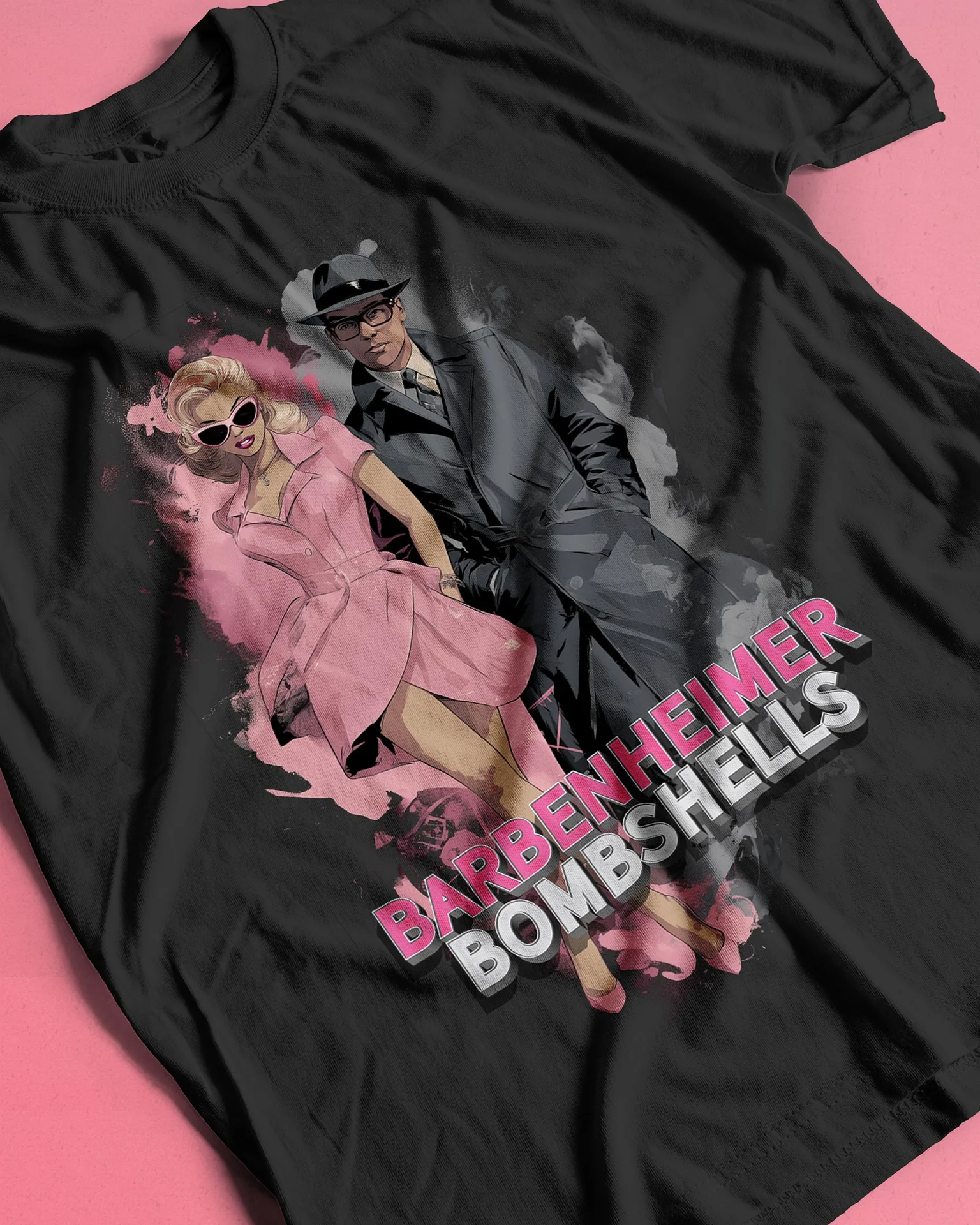 A woman in a pink dress and a man in a grey trench coat and fedora, with pink and white Barbenheimer Bombshells lettering, printed on a black shirt